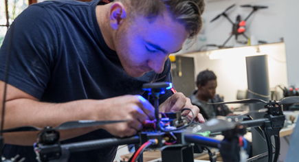 Image of a student working on a drone in a lab set up